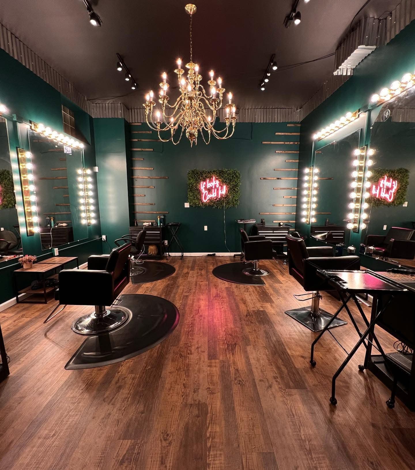Hair Mafia salon interior in Altoona with emerald walls, warm mirrors, and chandelier